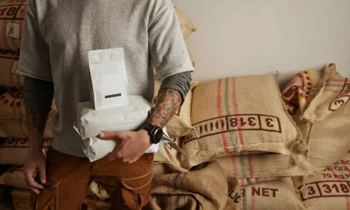 tattooed-barista-holds-blank-package-bags-with-fre-2024-09-17-14-02-03-utc-2